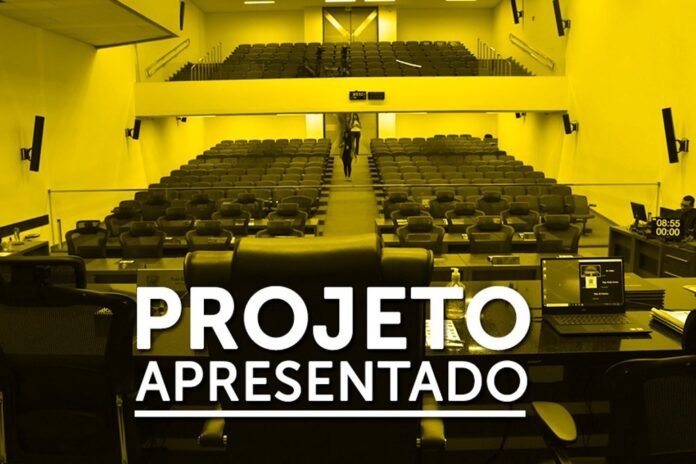 Lecture hall with empty rows of seats and a front desk; bold white text 'PROJETO APRESENTADO' across the image, indicating a project presentation banner.