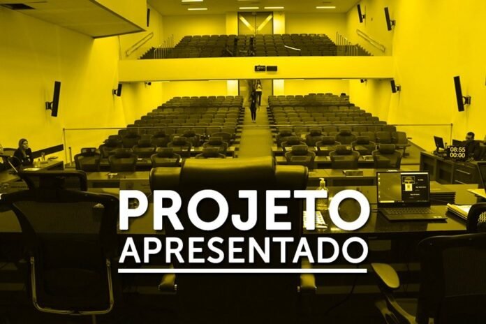 Auditorium viewed from the stage with empty seats and a desk in the foreground; large white text reads 'PROJETO APRESENTADO' across the image.