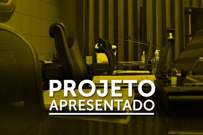 Office workspace with laptops on a long desk; overlay text 'PROJETO APRESENTADO'.