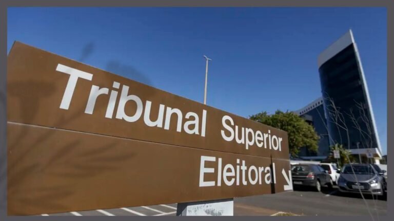 Sign reads 'Tribunal Superior Electoral' with an arrow, set against a modern building and parking lot under a blue sky.