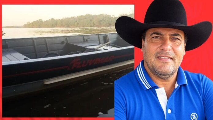 Man wearing a black cowboy hat and blue polo shirt, with a boat on a calm lake to his left against a red backdrop.