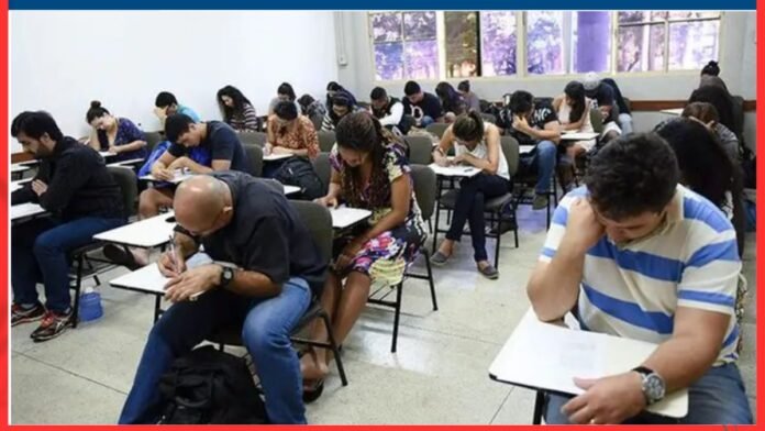 Students in a classroom taking an exam, heads down as they write at desks in rows.