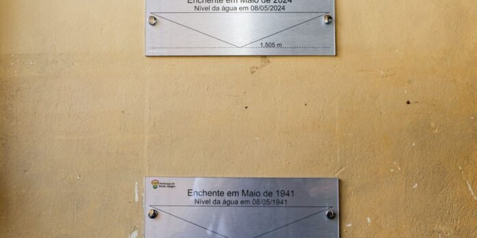 Metal flood level plaques on a yellow wall showing water levels for May 2024 and May 1941.