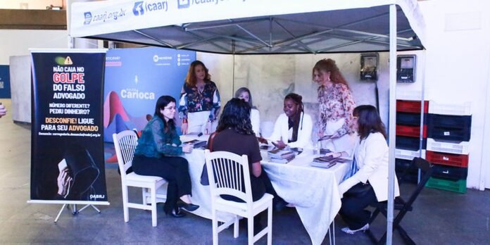 Group of people seated around a table under a tent, reviewing documents at a legal aid info booth.