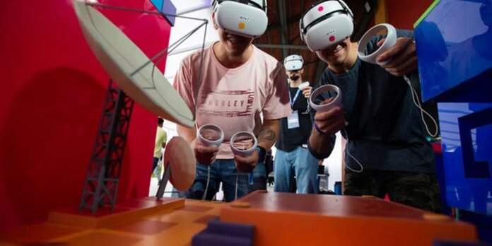 People wearing virtual reality headsets and holding circular motion controllers, engaged in a VR game at a colorful exhibit booth.