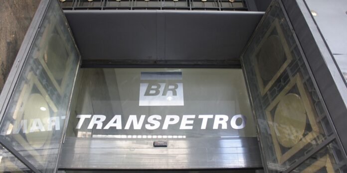 Glass elevator doors with a BR logo and the word TRANS-PETRO reflected on the glass, showing metallic interior and street reflections.