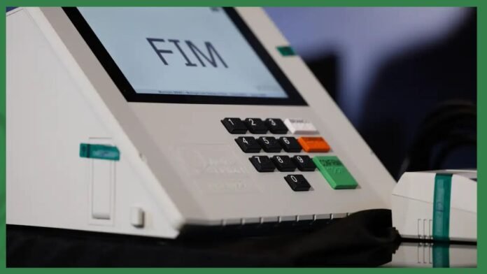Close-up of a point-of-sale terminal with a numeric keypad and a green enter button; screen shows 'FM'.