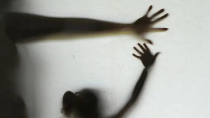 Shadowed person with arms extended, pressing against a white wall.