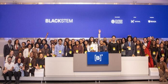 Diverse group of people posing on a stage with a blue backdrop reading BLACKSTEM and logos, gathered around a central podium.
